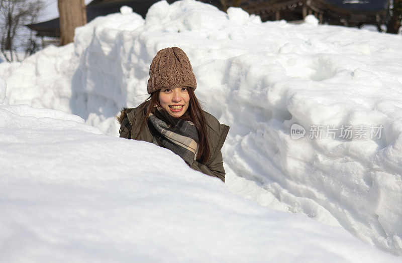 美丽的年轻女子在堆积的雪中放松