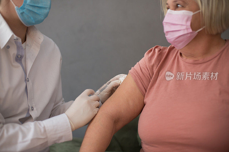 老年妇女接种疫苗治疗。女医生接种疫苗保护患者免受COVID-19感染。