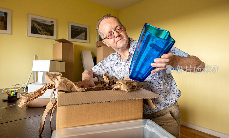 一个活跃的老人独自在空荡荡的公寓里搬家，检查花瓶，把东西包装在纸板箱里，看着怀旧的物品