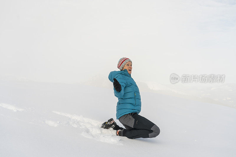 成熟的女人穿着皮大衣，跪在雪地里，对着天空