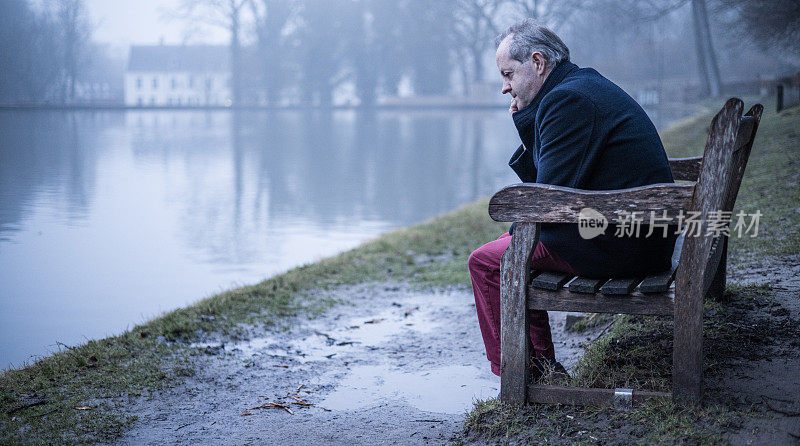 坐在公园长椅上头疼，一个中年男人独自在薄雾的森林里，在阴郁的气氛中孤独而被抛弃