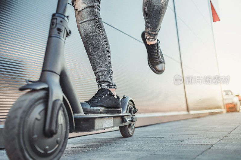 一个年轻人骑着他的电动滑板车出发了。技术、生态的移动性概念。一个骑着电动踏板车的潮人。