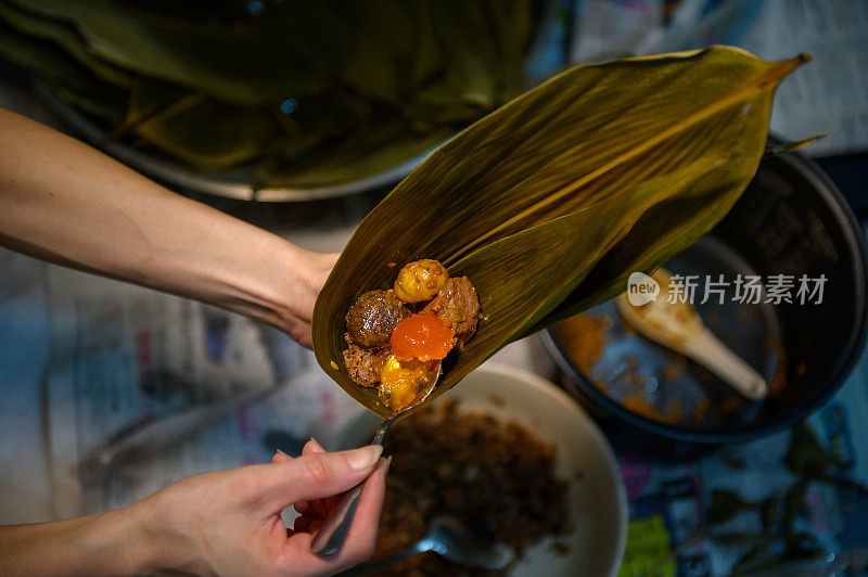 女人用手包粽子。端午节的传统食品