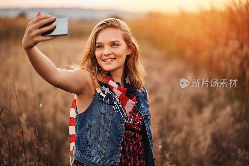 一名欢快的美国女性在户外用智能手机自拍