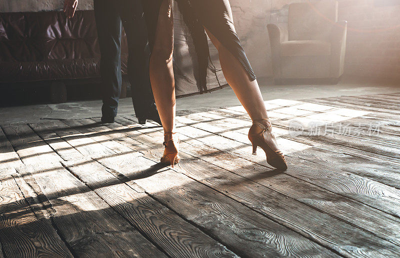 两名专业交际舞演员的两条腿在阁楼工作室跳舞。美丽的艺术表演与浓重的烟雾。运动生活的概念。激情和情感的舞蹈。