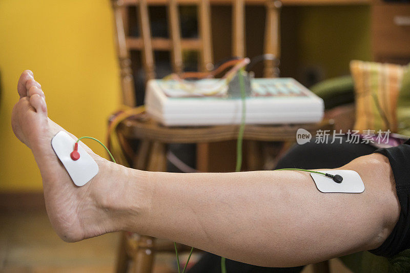 中年妇女使用电刺激她的腿