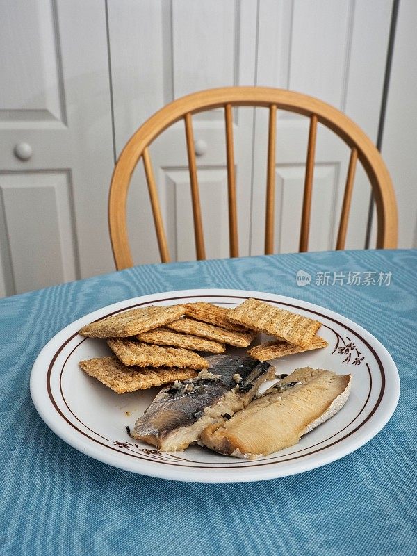 沙丁鱼和编织小麦饼干作为一种健康营养的小吃与桌子，椅子和用餐区背景