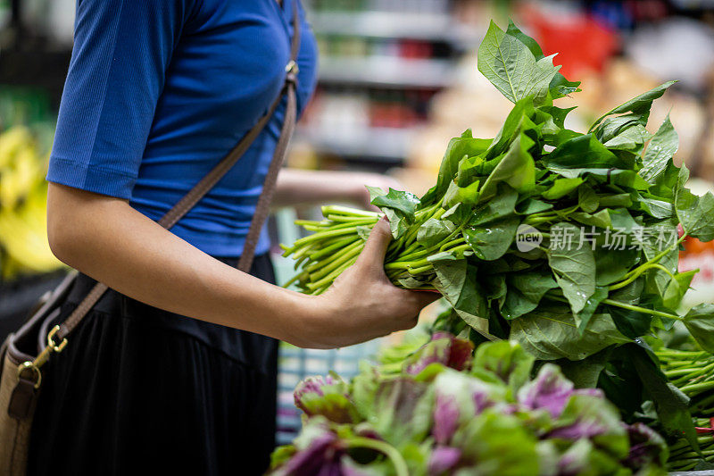 一位年轻女子在超级市场挑选蔬菜