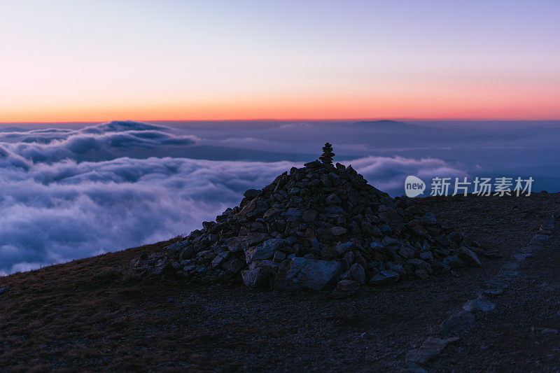 壮丽的风景与塔特拉山后日落。山顶有石塔，衬着蓝色和粉红色的天空和浮云