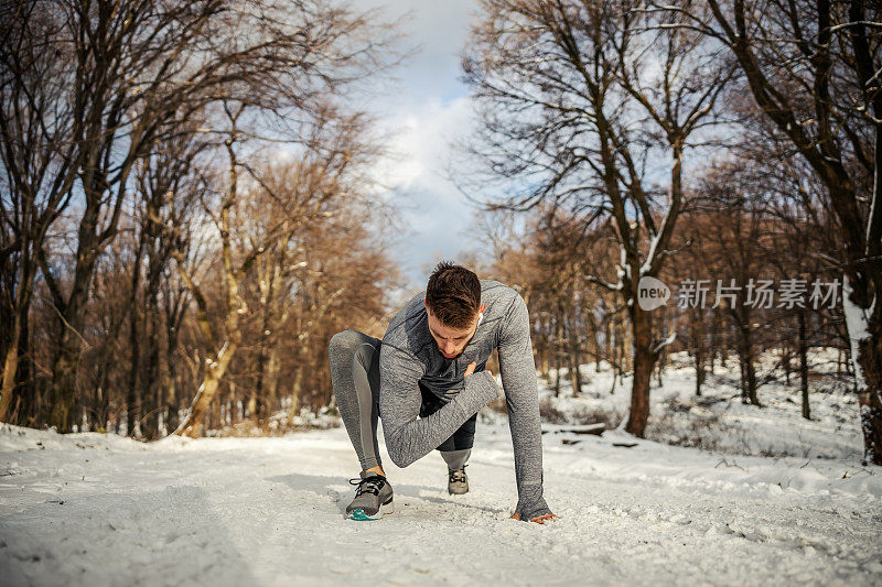 身体健康的运动员在雪天跪在大自然中做热身和伸展运动。冬季健身，健康生活方式