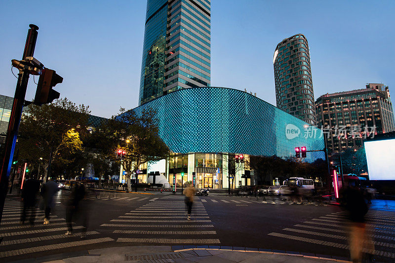 在中国上海，市中心繁忙的十字路口的夜景是高楼大厦和巨大的电子广告牌