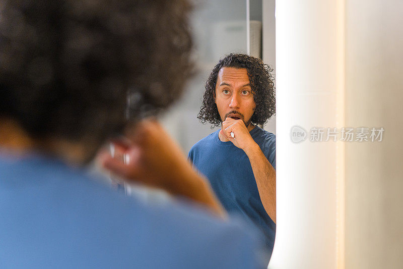 西班牙裔男子在镜子前刷牙