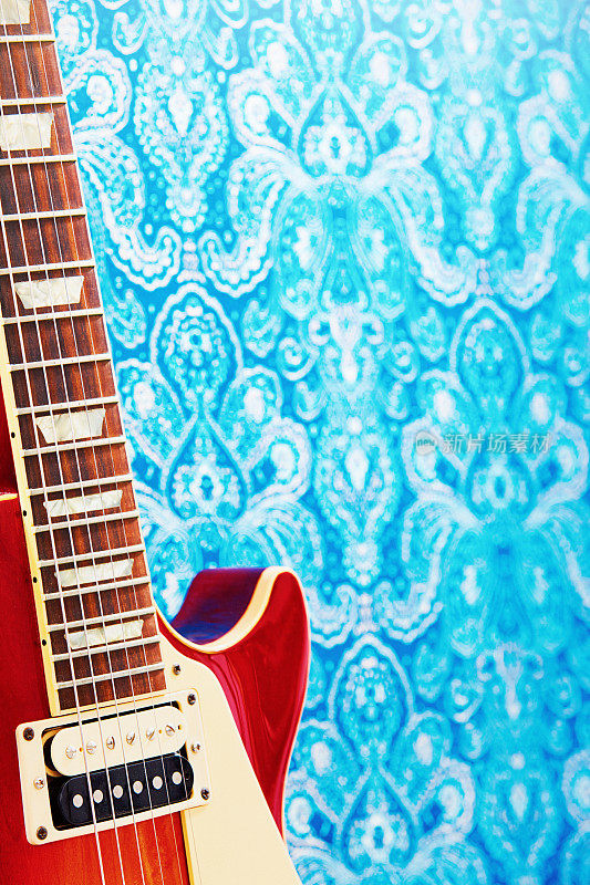 红色电吉他对一个华丽的蓝色图案的背景与复制空间