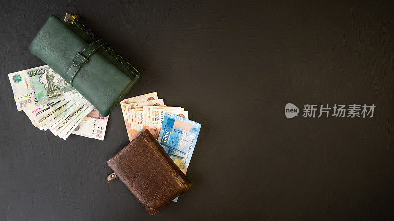 俄罗斯的钱。一个绿色和棕色钱包的特写，里面装满了5000卢布，2000卢布，1000卢布，500卢布。黑色背景。男士和女士的钱包。
