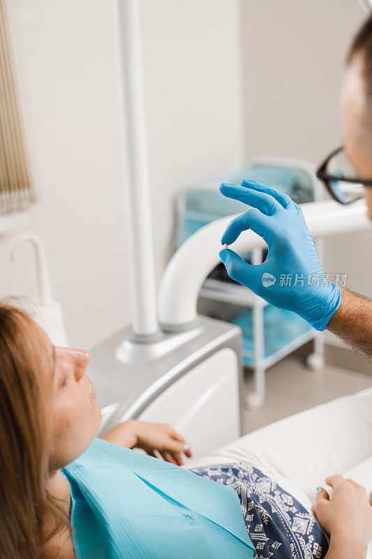 牙科医生在牙科诊所向妇女病人展示种植牙。牙医。向牙医咨询植牙及美白事宜。