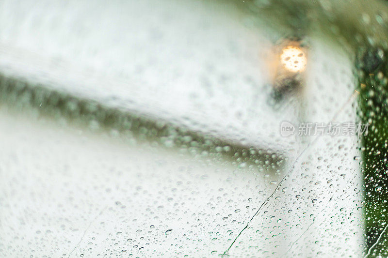 通过汽车挡风玻璃上的雨车库门视图-美国中西部在春天的天气和季节照片系列