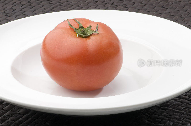 红色的番茄和叶子放在白色的盘子里