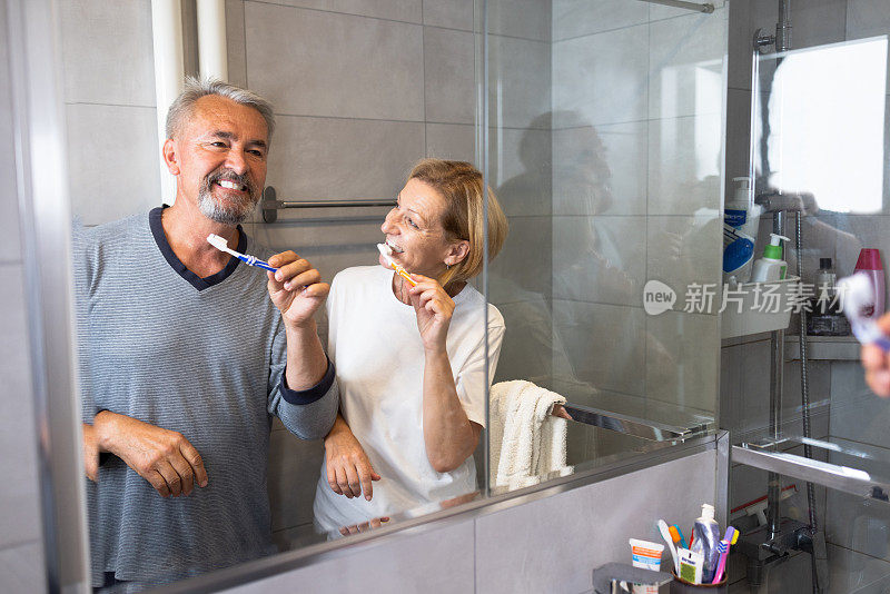 一对正在刷牙的老夫妇在镜子里的倒影