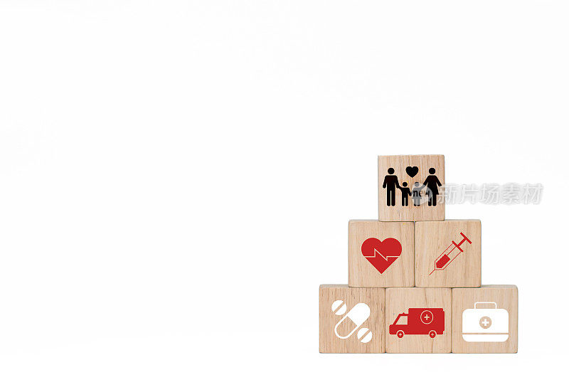 木制的方块传递着家庭和健康的故事。在白色的背景上，有红十字心形图标，注射器，药片，医药袋和救护车在白色的背景