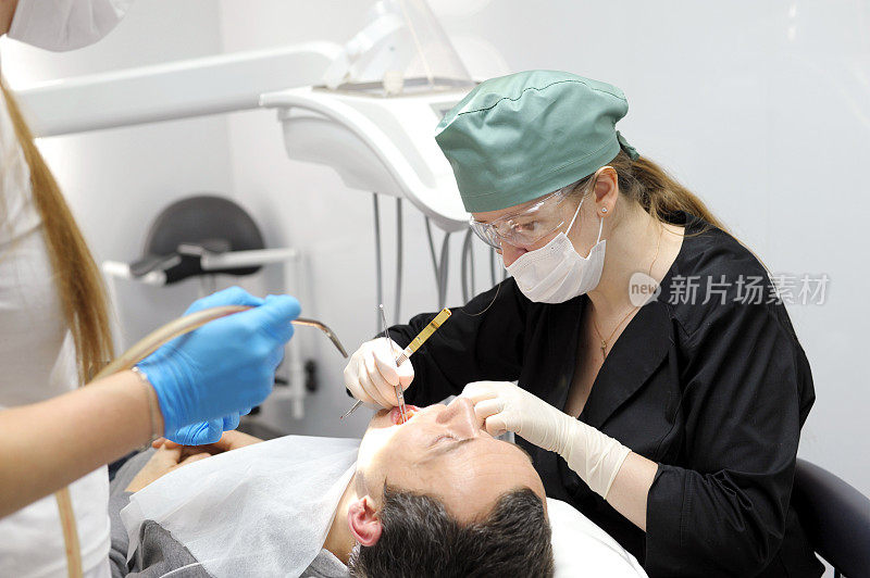 专业牙医为坐在医疗椅上的男病人补牙