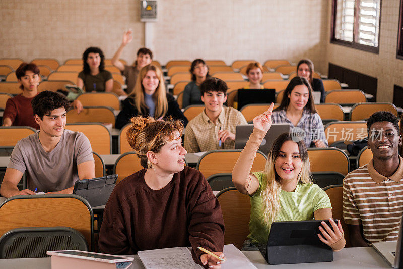 一群大学生在课堂上举手向老师提问