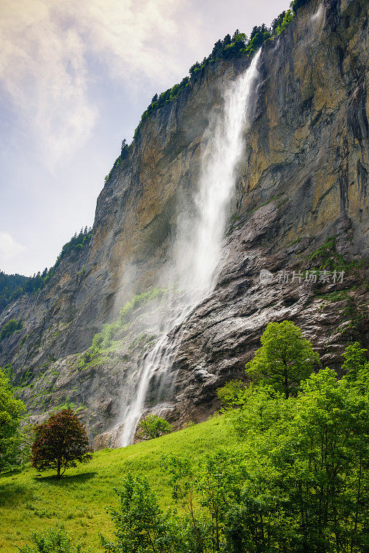 在一个晴朗的夏日，瑞士Lauterbrunnen村的Staubbachfall瀑布。高山旅游村庄Lauterbrunnen令人惊叹的景观。以高悬崖为背景的著名旅游村。