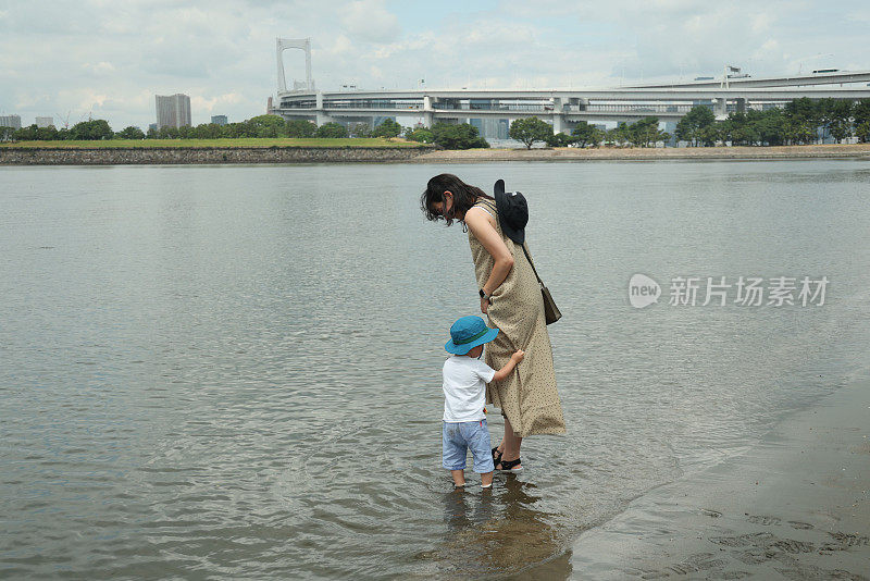 年轻的母亲带着她的小儿子在海滩上散步