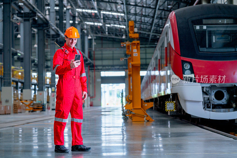 在电气或地铁工厂，专业技术人员站在火车附近，拿着手机看。