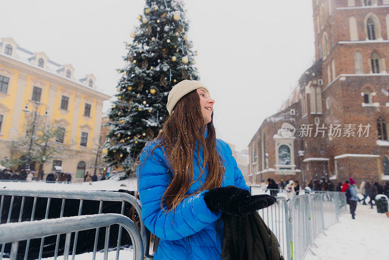 快乐的女人背着背包，在克拉科夫思考下雪的圣诞节