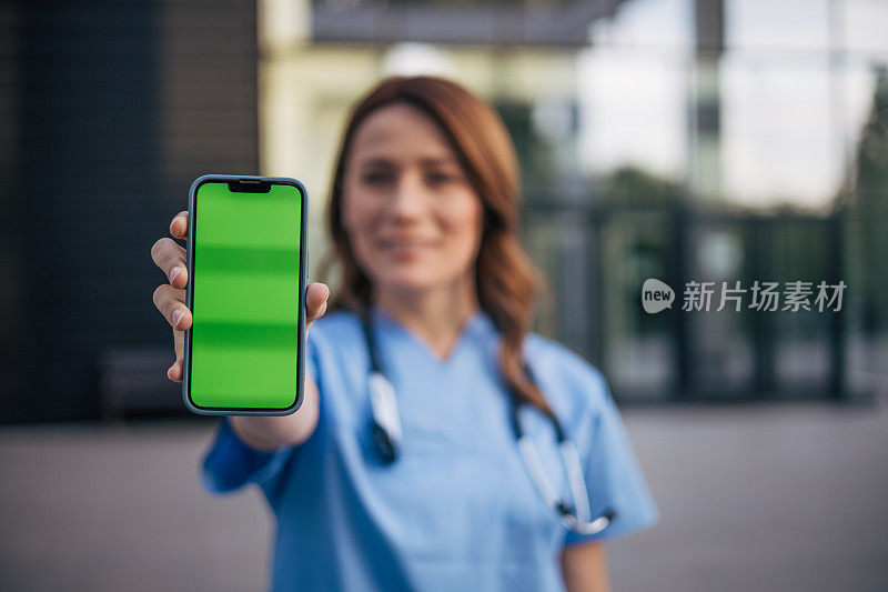 美丽的女医生站着拿着绿屏手机的肖像。