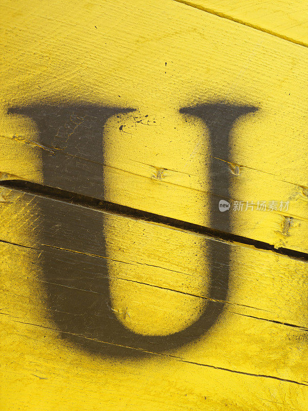 字母U画在黄色的木制背景上