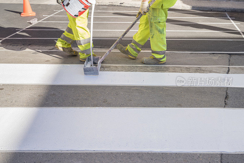 两个维修工人正在粉刷道路