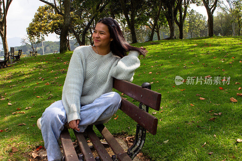 漂亮的年轻女子坐在木凳上，望着别处