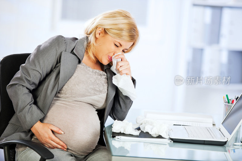 年轻怀孕的女商人正在擤鼻涕。