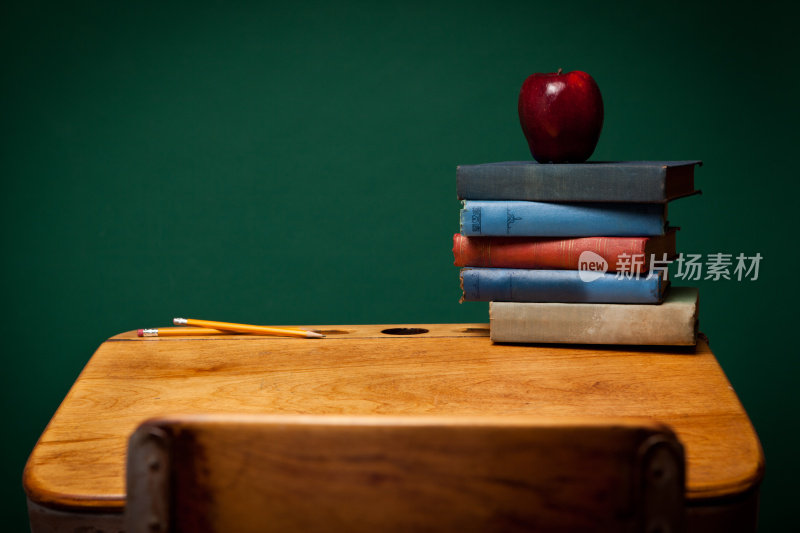 学校课桌上的苹果、铅笔和旧书