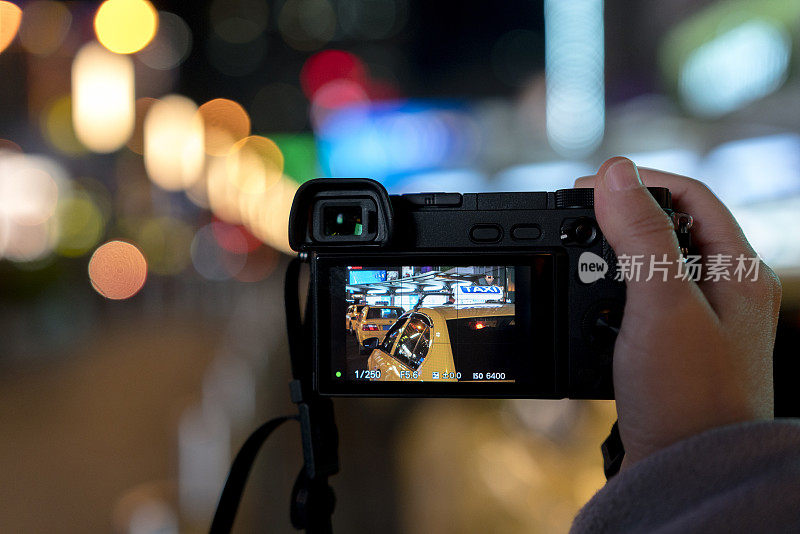 一名摄影师在拍摄晚上在市中心等车的照片