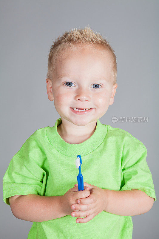微笑的小男孩拿着一把牙刷