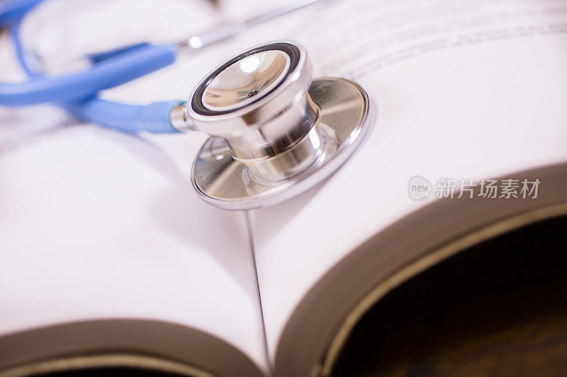 医生的听诊器的特写放在书桌上和书一起。阅读、学习。