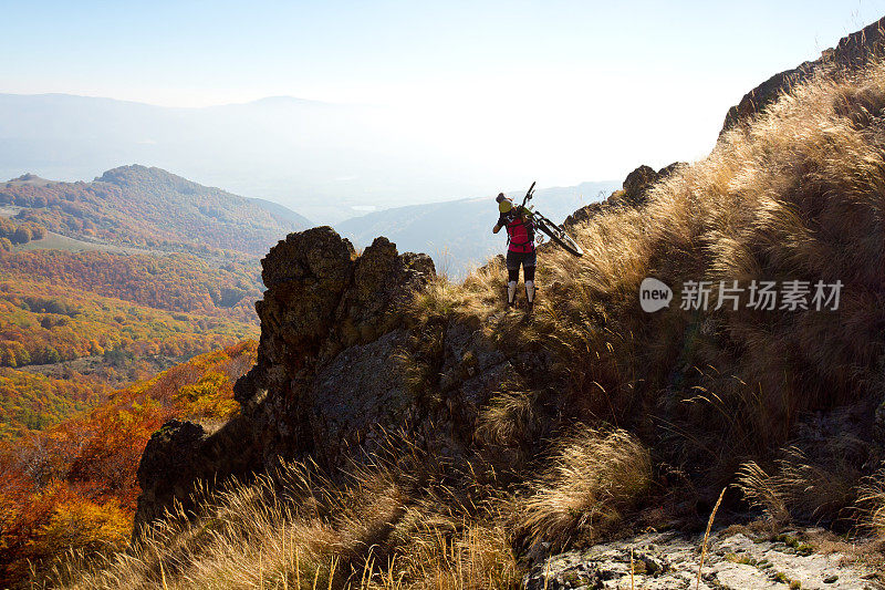 女自行车手背着她的自行车在陡峭的山区