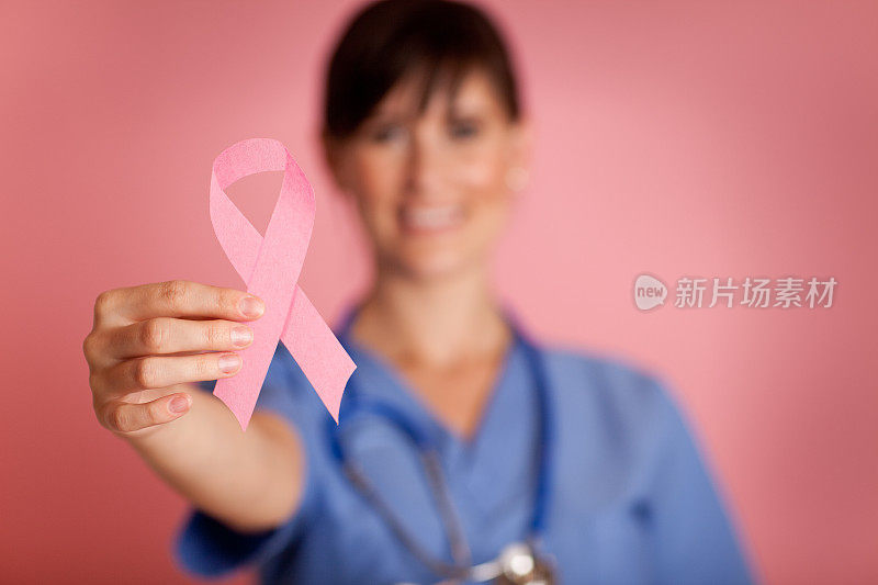 快乐的女护士手拿粉红乳腺癌意识丝带