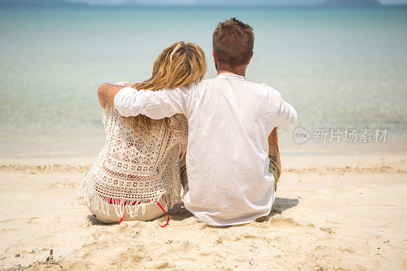 一对年轻夫妇在热带海滩上拥抱