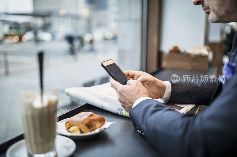 成熟的商人在咖啡馆用手机