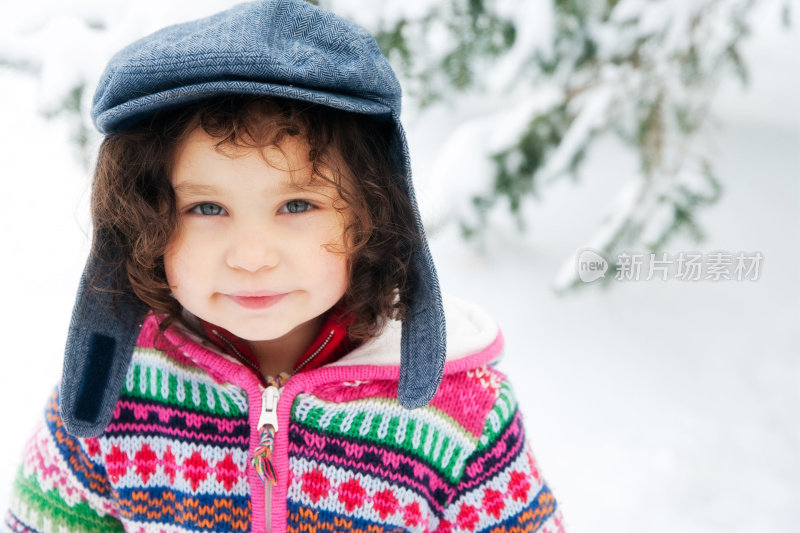 美丽的小女孩戴着圣诞老人的帽子在雪地里玩