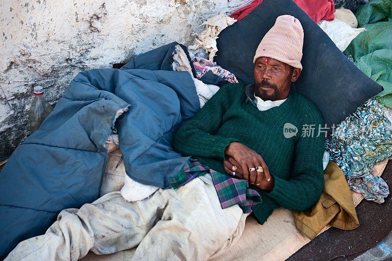 一个乞丐躺在印度寺庙附近的人行道上