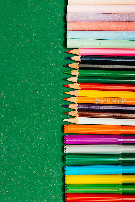 学校物品，铅笔，蜡笔和粉笔在空的学校黑板上