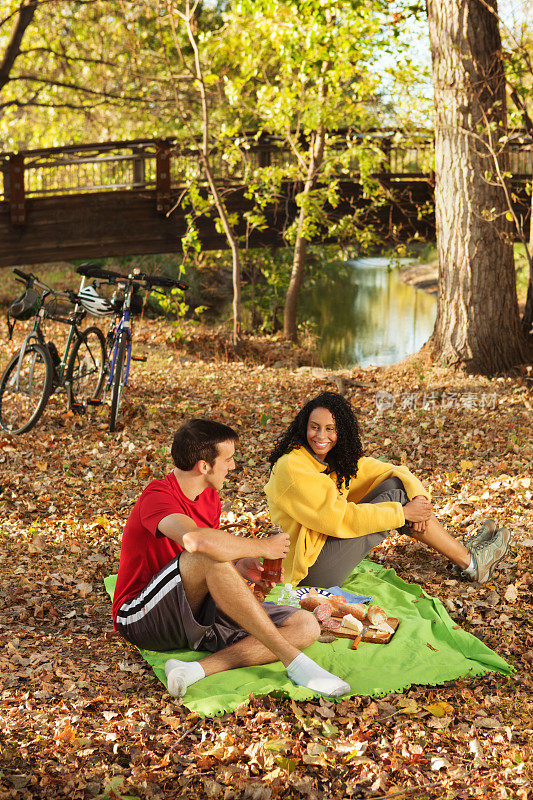 骑自行车的人沿着秋色的小溪休息和野餐