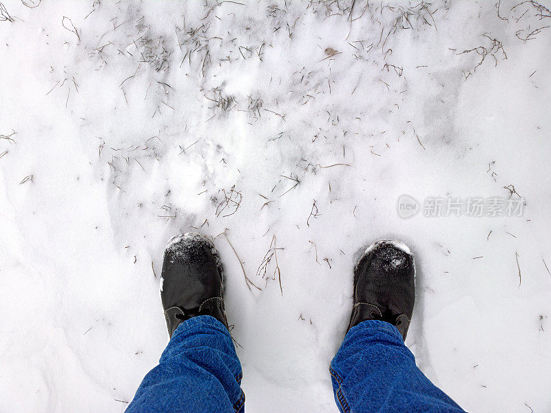脚踩在雪地里干燥的植物上。