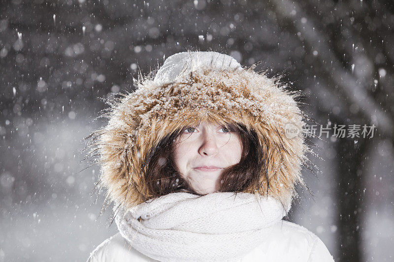 雪下穿着白色夹克的漂亮少女