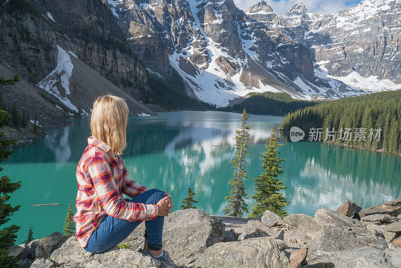 年轻女子徒步旅行者在岩石之上的山湖