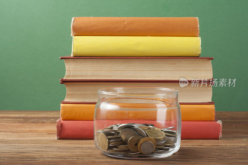 玻璃罐里的硬币，木桌上的一叠书。储蓄、理财、教育理念。